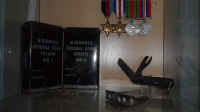 UK PLANK:FLARE PISTOL AMMO BLIKJES,ENFIELD CLIP,ZAKMES,ROYAL ARTILLERY EMBLEEMPJES EN MEDAILLE'S O.A. 1939-1945 STAR,THE FRANCE AND GERMANY STAR,THE DEFENCE MEDAL EN 1939-1945 MEDAL